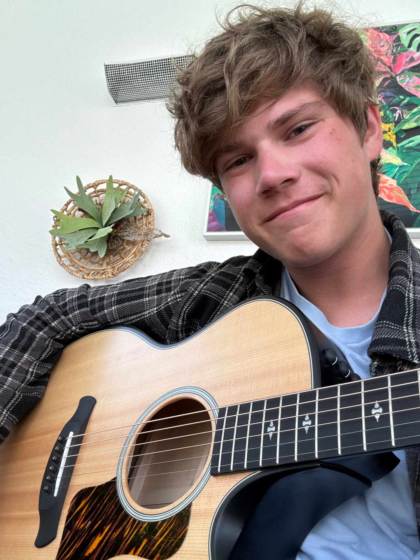 Young teenager smiling while playing acoustic guitar in warm afternoon light